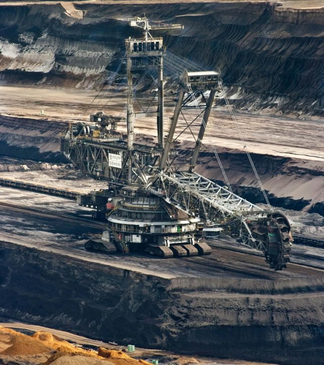 brown-coal-energy-garzweiler-bucket-wheel-excavators-60008-60008 Large bucket wheel excavator operating in an open-pit mine with layered soil and coal.